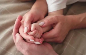 Three hands holding each other gently