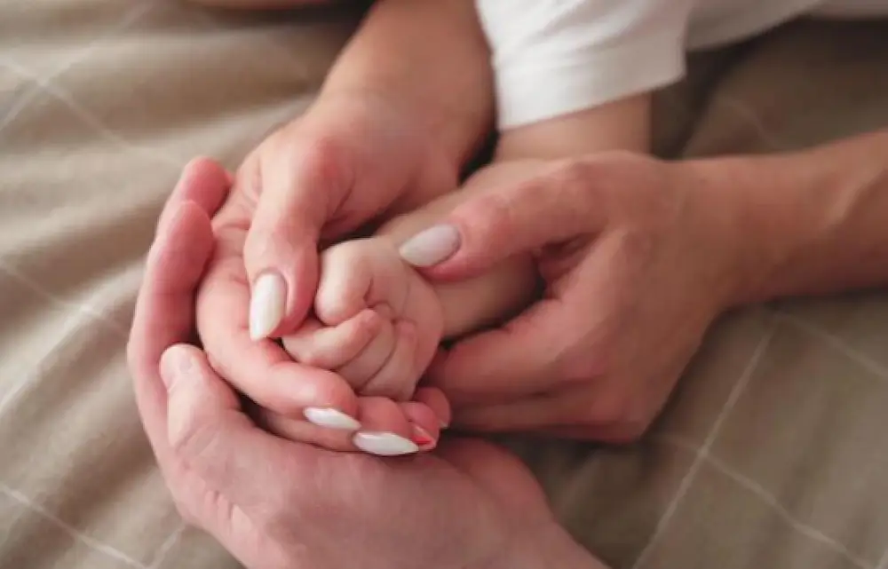 Three hands holding each other gently